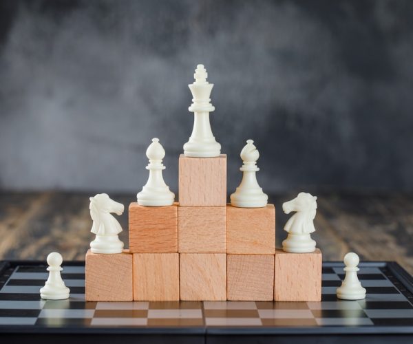 business-hierarchy-concept-with-chessboard-figures-pyramid-wooden-blocks-foggy-wooden-table-side-view_176474-9254